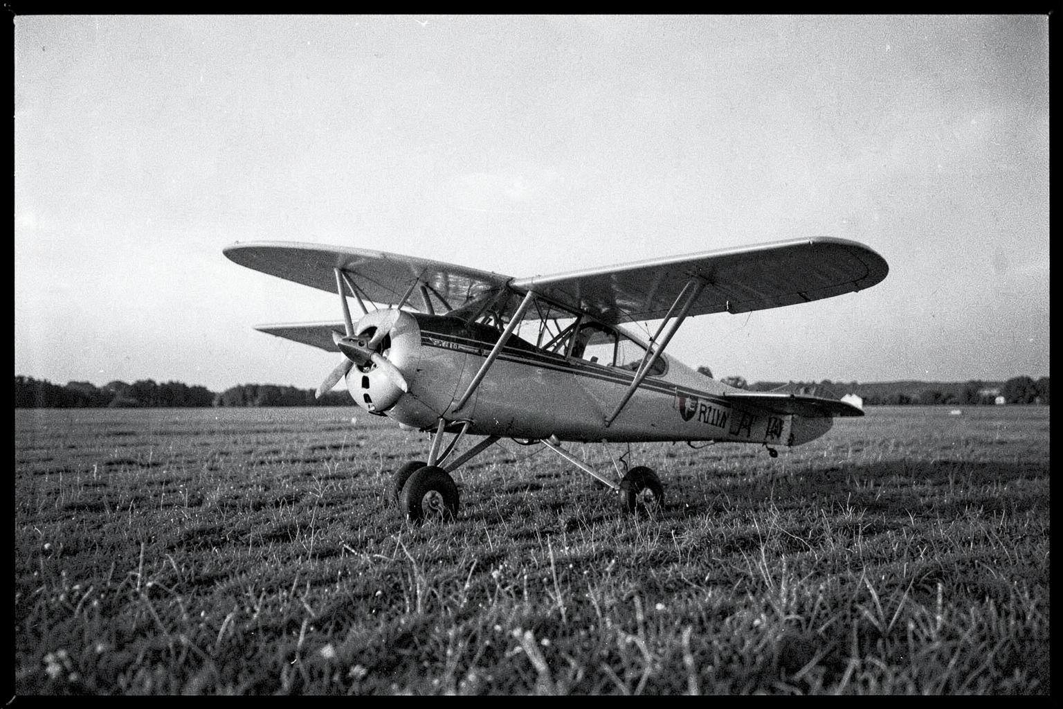 A 1920s single-engine monoplane on a grass airfield